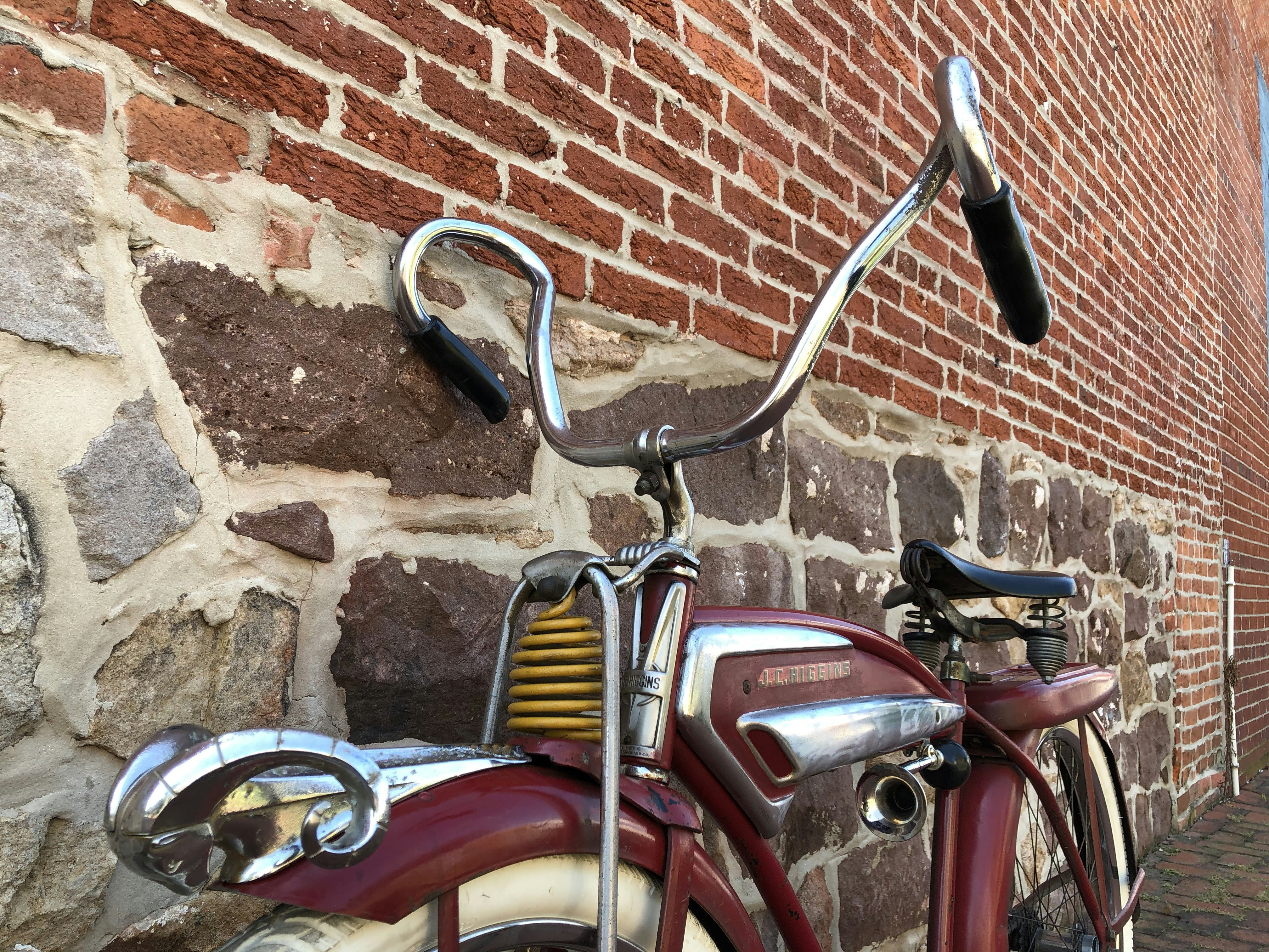 red and silver bicycle beside brown brick wall